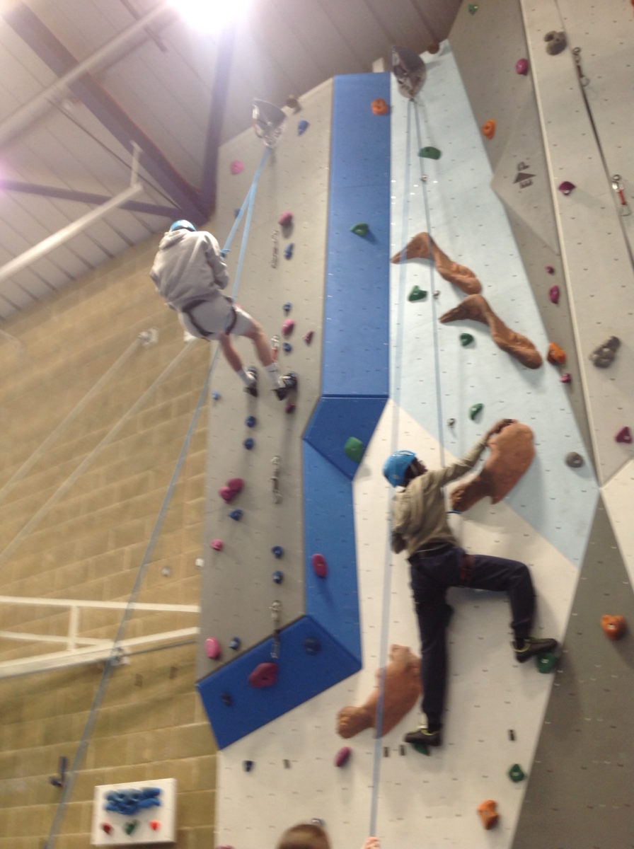 Two Stationers' Crown Woods Academy students are pictured participating in rock climbing, attached to safety harnesses.