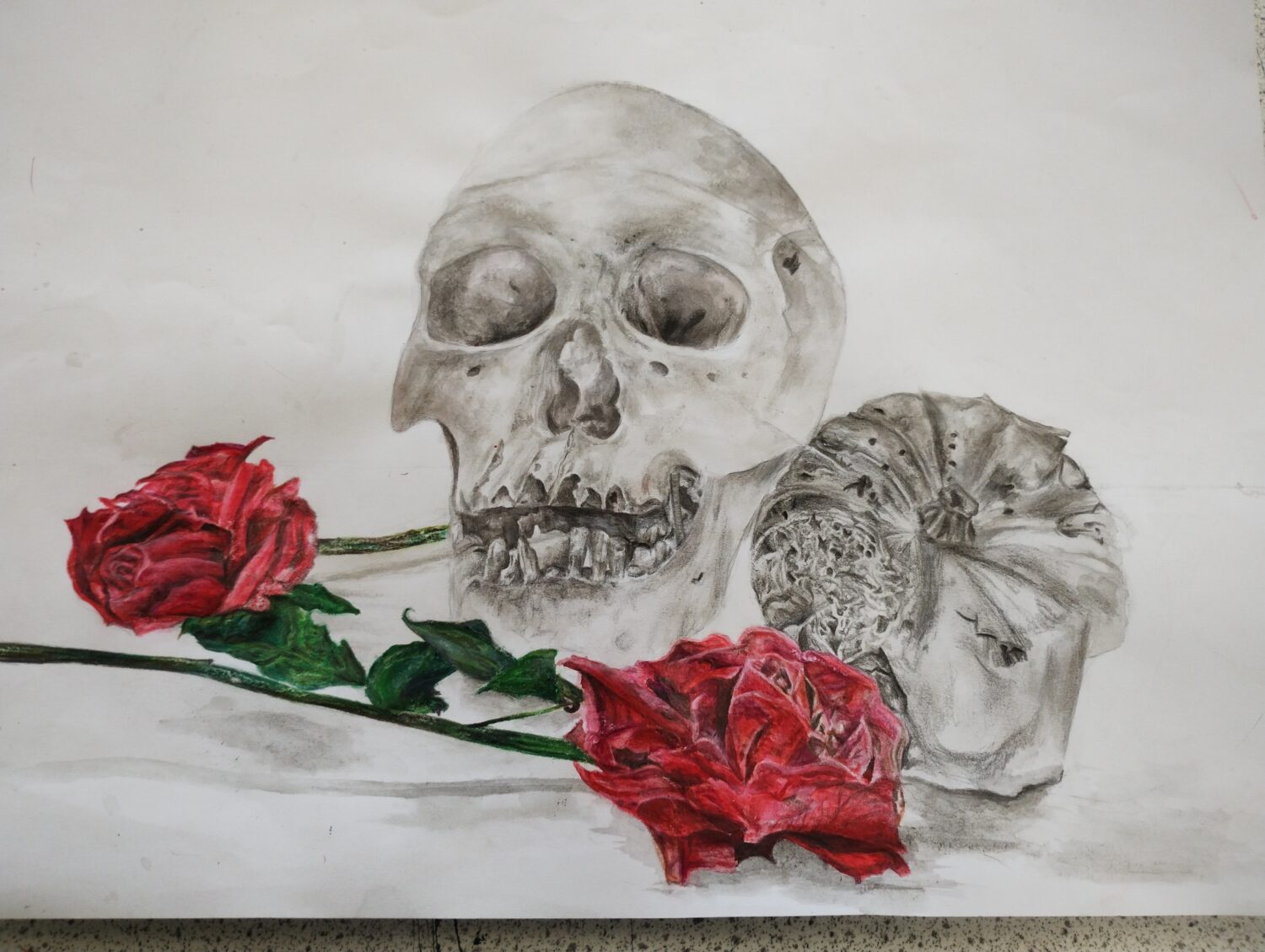 A student's artwork of a skull, pumpkin and two roses